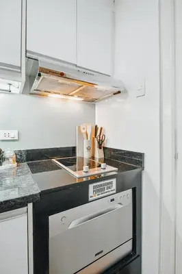 a kitchen with white cabinets and a stove top oven at Coastal Studio in KL Tower Serviced Residences, Greenbelt, Makati! Maximum capacity 5 pax! in Manila