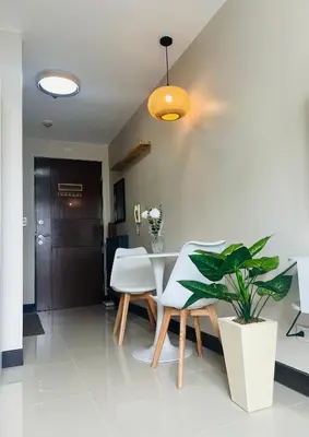 a dining room with a white table and a plant at Astra Heights Staycation in Manila