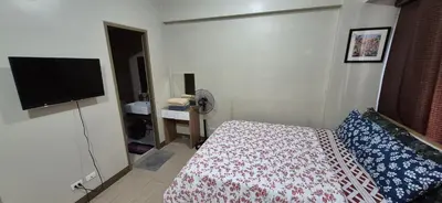 a hotel room with a bed and a flat screen tv at Rooms in Pasay Manila Nearest To Airport Terminal 3 in Manila
