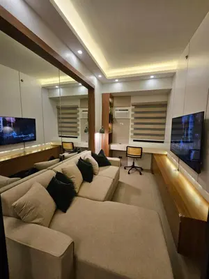 a living room with a large couch and a television at Luxury apartment at Bloom Residences in Manila