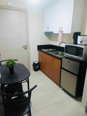 a small kitchen with a table and a microwave at Rose 150newport pasay in Manila