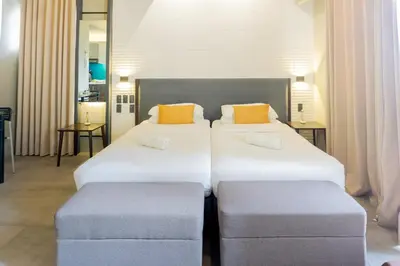 two beds in a hotel room with two ottomans at Spacious Condo with 50in TV & Netflix, Near Malls in Manila
