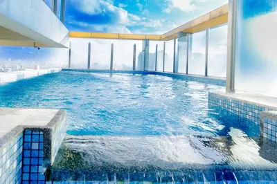 a swimming pool on the top of a building at Spacious Condo with 50in TV & Netflix, Near Malls in Manila