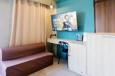 a room with a desk and a tv on the wall at Spacious Condo with 50in TV & Netflix, Near Malls in Manila