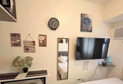 a tv on a wall with a mirror and a clock at JJMC HOMESTAY 28 With Netflix and Unli Wifi in Manila