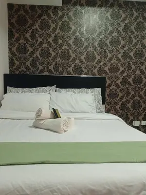 a bed with a book and a pair of slippers on it at Grand Riviera Condotel Near St lukes Medical Center in Manila