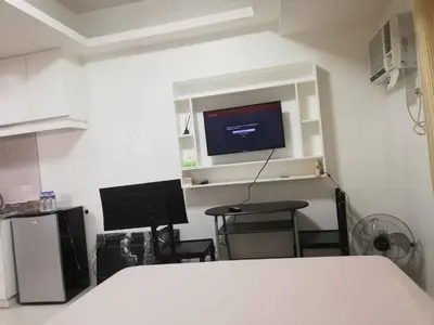 a bedroom with a bed and a tv on a wall at Grand Riviera Condotel Near St lukes Medical Center in Manila