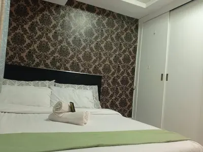 a bedroom with a bed with two towels on it at Grand Riviera Condotel Near St lukes Medical Center in Manila