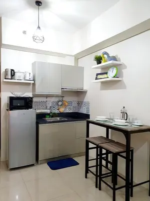 a kitchen with a refrigerator and a table with stools at Zeke Suite At Beacon Tower Amorsolo unit 2330 in Manila