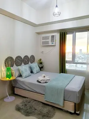a bedroom with a large bed with a window at Zeke Suite At Beacon Tower Amorsolo unit 2330 in Manila