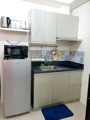 a kitchen with white cabinets and a microwave and a refrigerator at Zeke Suite At Beacon Tower Amorsolo unit 2330 in Manila