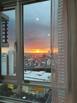 a view of a city from a window with a sunset at Zeke Suite At Beacon Tower Amorsolo unit 2330 in Manila