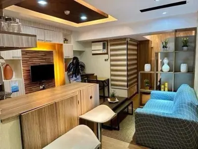 a living room with a blue couch and a television at Staycation at Starmall in Manila