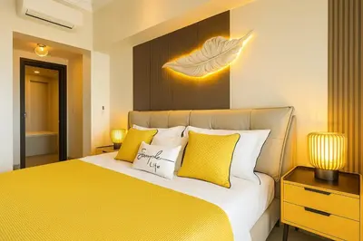 a bedroom with a bed with yellow and white pillows at Luxury & Modern 2BR Penthouse in BGC in Manila