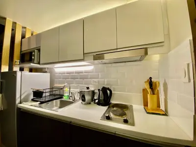 a white kitchen with a sink and a refrigerator at Edin's Home in Manila