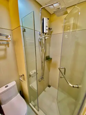 a bathroom with a glass shower and a toilet at Calix Suite in Manila