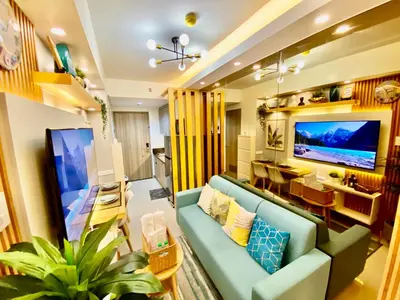 a living room with a blue couch and a television at Calix Suite in Manila