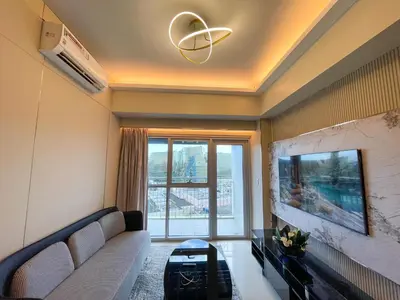 a living room with a couch and a large window at Luxury and Modern 1 Bedroom near Solaire, Okada in Manila
