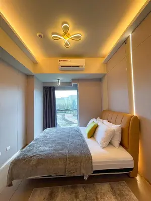 a bedroom with a bed with a ceiling fan and a window at Luxury Suites near Okada, Solaire, City of Dreams in Manila