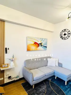 a living room with a couch and a clock on the wall at Condotels near NAIA in Manila