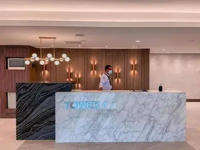 a man standing behind a counter in a hotel lobby at Furnished Condo Unit-Green2 PoolWifiNetflix in Dasmariñas