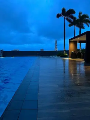 a swimming pool with palm trees and a building at Condo Near World Trade, Star City and PICC - Amazing Breeze in Manila