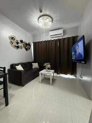 a living room with a couch and a flat screen tv at Staycation By Abii in Manila