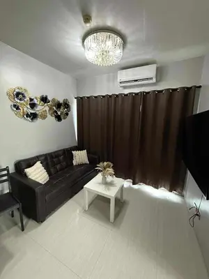 a living room with a black couch and a table at Staycation By Abii in Manila