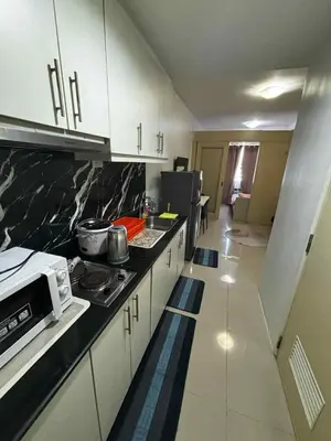 a kitchen with white cabinets and a black counter top at Elizas place in Manila