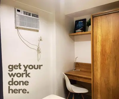 a room with a desk and a fan on a wall at FLAT ESHRA - Cozy Bright 1-BR in Manila