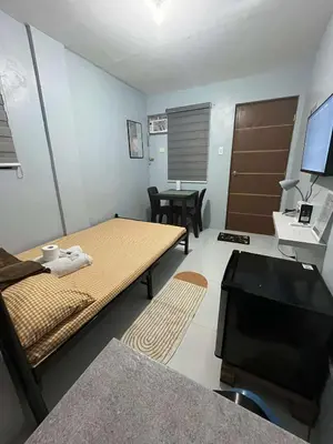 a room with a bed and a table and a television at RJ Wallfan Studio Transient in Napico, Lifehomes Pasig City in Manila