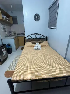 a bed in a room with a clock on the wall at RJ Wallfan Studio Transient in Napico, Lifehomes Pasig City in Manila