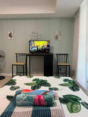 a room with a bed with a television and chairs at azure 1bedroom pool view in Manila