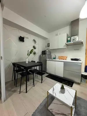 a living room with a table and a kitchen at azure 1bedroom pool view in Manila