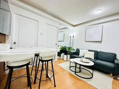 a living room with a green couch and a table at Unwind Oasis Two Bedroom Free Pool Access in Manila