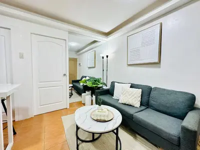 a living room with a blue couch and a table at Unwind Oasis Two Bedroom Free Pool Access in Manila
