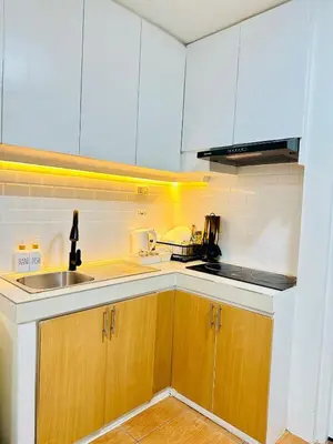 a kitchen with white cabinets and a sink and a counter at Unwind Oasis Two Bedroom Free Pool Access in Manila