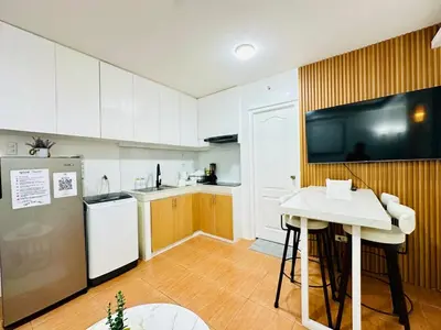 a kitchen with a refrigerator and a table and a tv at Unwind Oasis Two Bedroom Free Pool Access in Manila