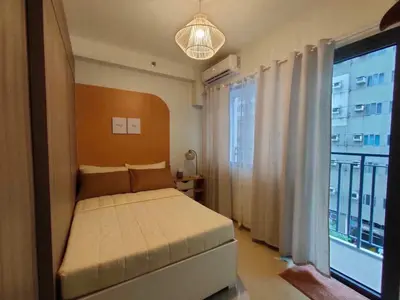 a bedroom with a bed and a large window at shore 1bedroom with balcony in Manila