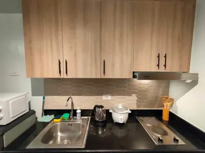a kitchen counter with a sink and a microwave at shore 1bedroom with balcony in Manila