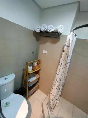 a bathroom with a toilet and a shelf with towels at shore 1bedroom with balcony in Manila