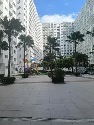 a park with palm trees and a playground and buildings at Shore residences Tower D pool view Unit in Manila