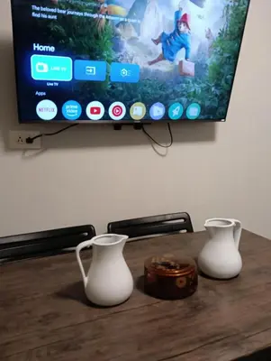 a table with two white vases and a tv at Shore residences Tower D pool view Unit in Manila