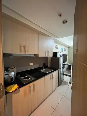 a kitchen with wooden cabinets and a black counter top at Breeze Residences pasay near naia airport in Manila