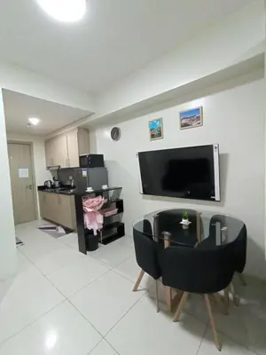 a living room with a tv and a table with chairs at Breeze Residences pasay near naia airport in Manila