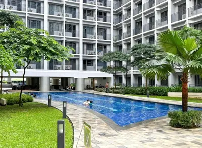 a hotel with a swimming pool in front of a building at Staycation by the Shore in Manila