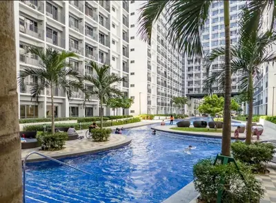 a large swimming pool with palm trees and buildings at Staycation by the Shore in Manila