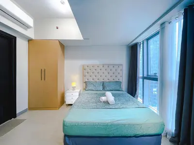 a bedroom with a large bed with a large window at 1 BR Cozy unit Uptown Parksuites BGC in Manila