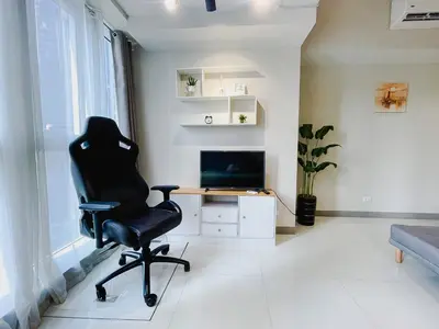 a black chair in a living room with a desk at 1 BR Cozy unit Uptown Parksuites BGC in Manila