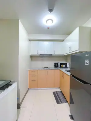 a kitchen with white cabinets and a stainless steel refrigerator at 1 BR Cozy unit Uptown Parksuites BGC in Manila